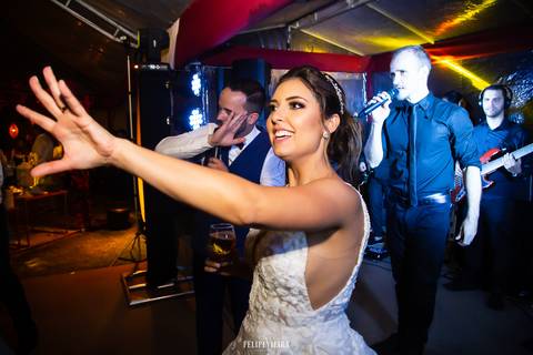 noiva na pista dançando com o noivo em frente ao palco da banda na festa de casamento'