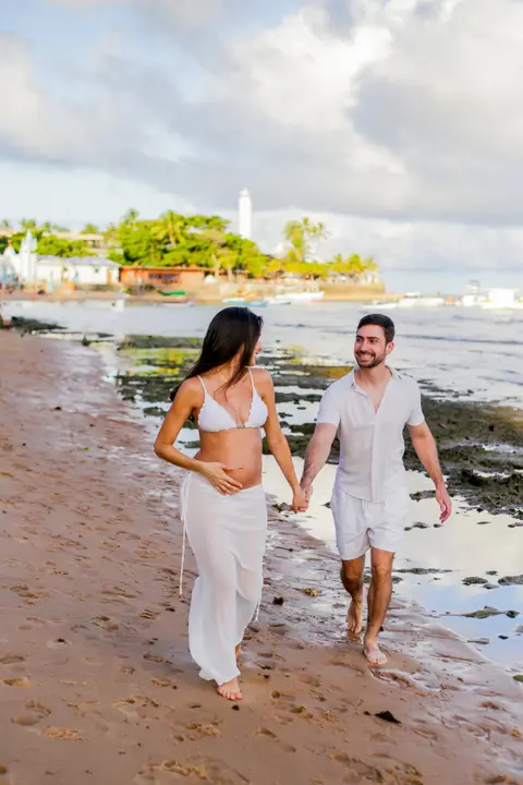 Ensaio fotográfico deslumbrante em Praia do Forte-Ba captura o amor e a expectativa do casal à espera do bebê.'
