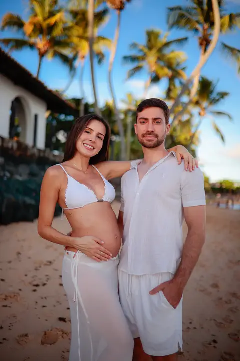 Ensaio fotográfico deslumbrante em Praia do Forte-Ba captura o amor e a expectativa do casal à espera do bebê.'
