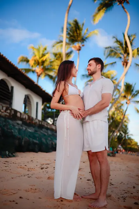 Ensaio fotográfico deslumbrante em Praia do Forte-Ba captura o amor e a expectativa do casal à espera do bebê.'