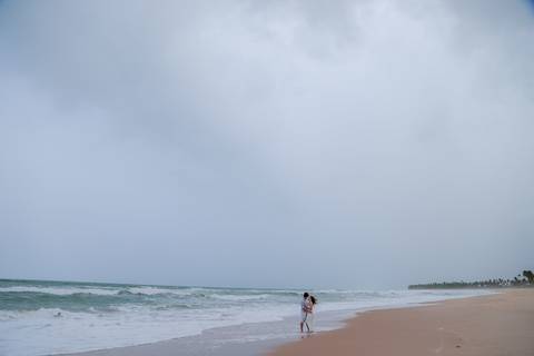 Casal se banha de mar e chuva em ensaio romântico na Bahia. Registro autêntico para quem busca fotografia de casamento com emoção.'