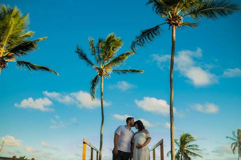 Família em ensaio gestante entre palmeiras e céu azul, no litoral norte da Bahia, com fotografia assinada por Waldyr Lantyer, fotógrafo em Praia do Forte Bahia, próximo ao resort Iberostar.

Casal com seu cachorro no jardim de casa de veraneio em Barra do'