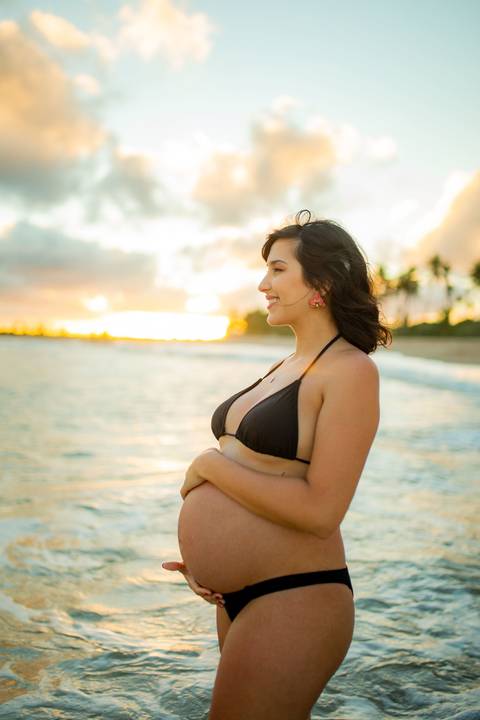 Gestante contemplando o mar com vestido branco esvoaçante, na varanda de casa próxima ao Iberostar, em ensaio realizado por Waldyr Lantyer, fotógrafo da Praia do Forteasal em abraço carinhoso à beira-mar, com vegetação tropical ao fundo, capturad Bahia.

'