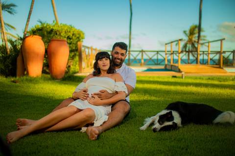 Gestante de branco deitada na rede com o marido em casa de praia em Barra do Jacuípe, próximo ao Iberostar, em ensaio realizado por Waldyr Lantyer, fotógrafo na Praia do Forte Bahia.'
