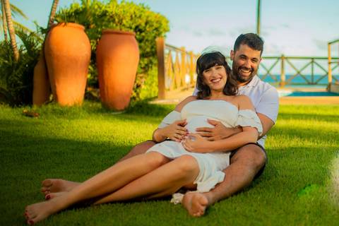 Gestante de branco deitada na rede com o marido em casa de praia em Barra do Jacuípe, próximo ao Iberostar, em ensaio realizado por Waldyr Lantyer, fotógrafo na Praia do Forte Bahia.'