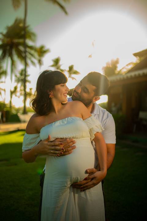 Casal mineiro trocando carinho na rede em varanda com vista para o mar, em ensaio gestacional produzido por Waldyr Lantyer, fotógrafo especializado na Praia do Forte Bahia e região do Iberostar.'