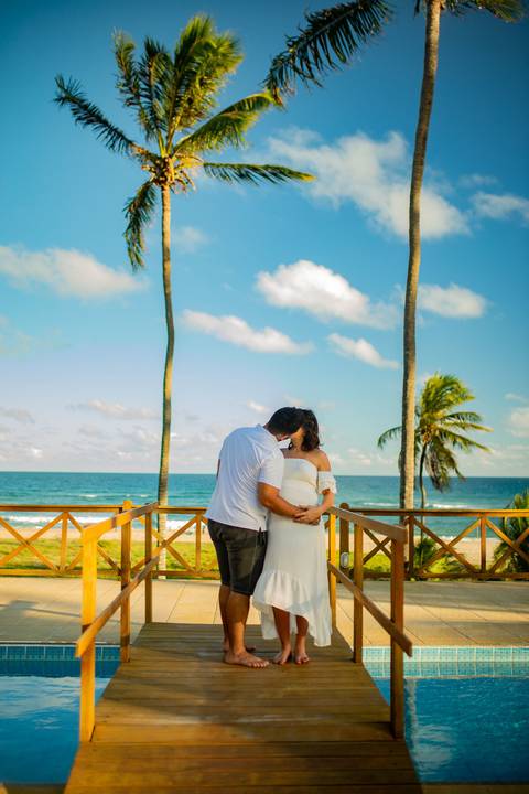 Família em ensaio gestante entre palmeiras e céu azul, no litoral norte da Bahia, com fotografia assinada por Waldyr Lantyer, fotógrafo em Praia do Forte Bahia, próximo ao resort Iberostar.

Casal com seu cachorro no jardim de casa de veraneio em Barra do'