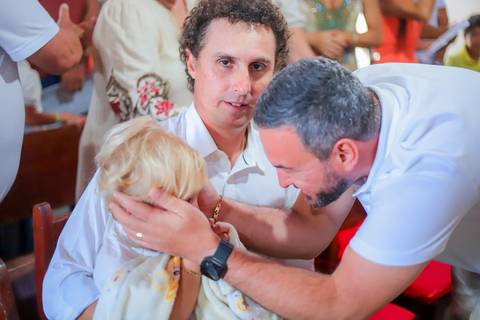 Ensaio de batizado com pais e padrinhos em cenário natural na Praia do Forte — experiência de fé e conexão familiar.'