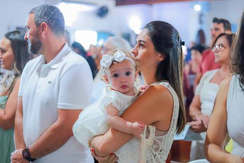 Ensaio de família em Praia do Forte com pais e filha durante o batismo — fotografia afetiva e natural realizada por Waldyr Lantyer.'