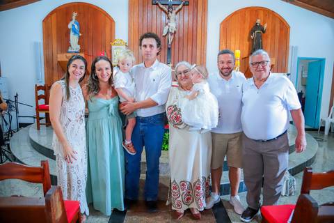 Fotografia ao ar livre na Bahia durante batizado familiar — cenário tropical e luz natural favorecem o registro afetivo.'