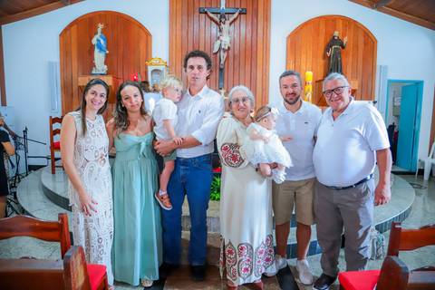 Fotografia ao ar livre na Bahia durante batizado familiar — cenário tropical e luz natural favorecem o registro afetivo.'