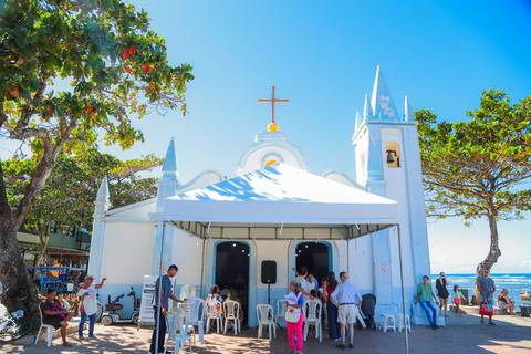 Ensaio de família em Praia do Forte com pais e filha durante o batismo — fotografia afetiva e natural realizada por Waldyr Lantyer.'