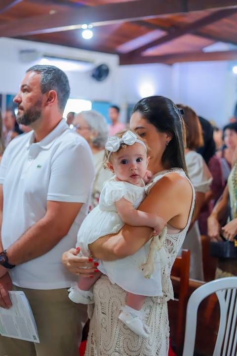 Ensaio de família em Praia do Forte com pais e filha durante o batismo — fotografia afetiva e natural realizada por Waldyr Lantyer.'