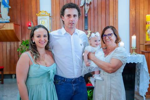 Fotografia ao ar livre na Bahia durante batizado familiar — cenário tropical e luz natural favorecem o registro afetivo.'