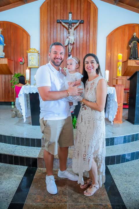 Fotografia ao ar livre na Bahia durante batizado familiar — cenário tropical e luz natural favorecem o registro afetivo.'