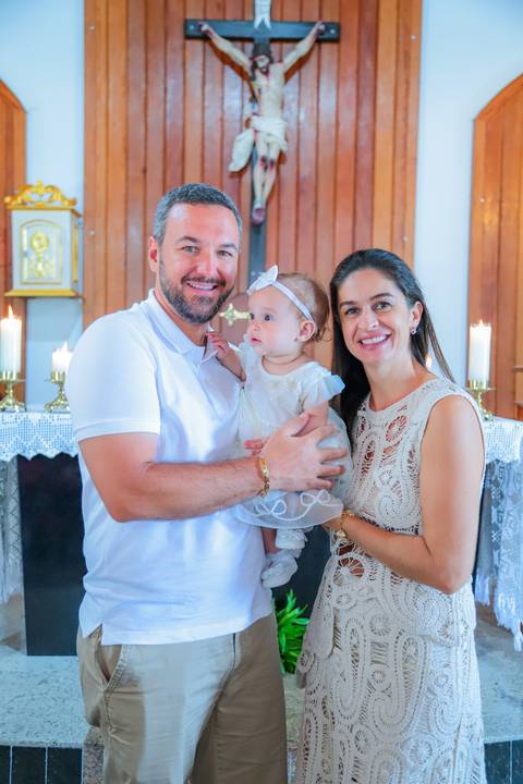 Fotografia ao ar livre na Bahia durante batizado familiar — cenário tropical e luz natural favorecem o registro afetivo.'