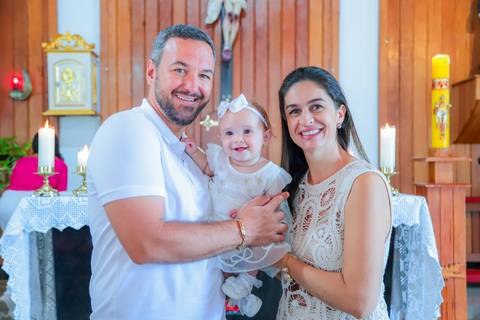 Fotografia ao ar livre na Bahia durante batizado familiar — cenário tropical e luz natural favorecem o registro afetivo.'