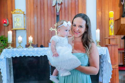 Fotografia ao ar livre na Bahia durante batizado familiar — cenário tropical e luz natural favorecem o registro afetivo.'