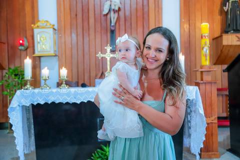 Fotografia ao ar livre na Bahia durante batizado familiar — cenário tropical e luz natural favorecem o registro afetivo.'