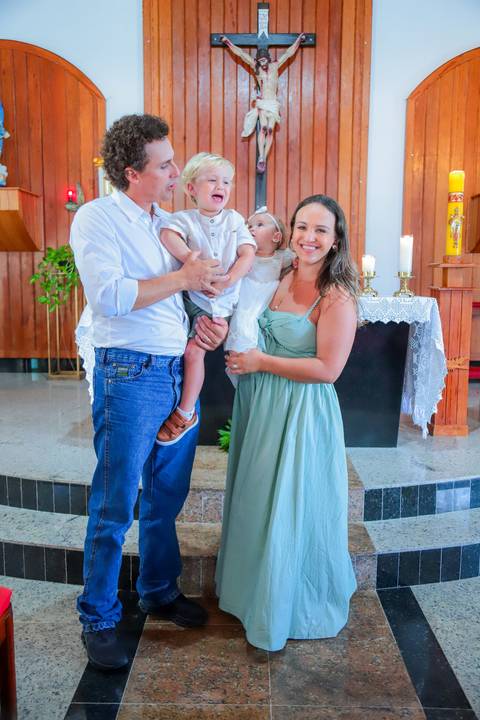 Fotografia ao ar livre na Bahia durante batizado familiar — cenário tropical e luz natural favorecem o registro afetivo.'