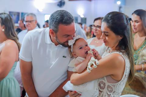 Ensaio de família em Praia do Forte com pais e filha durante o batismo — fotografia afetiva e natural realizada por Waldyr Lantyer.'