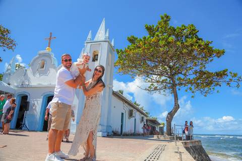 Entrada da igreja histórica de Praia do Forte no momento do batizado infantil — fotografia documental.'