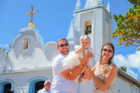 Entrada da igreja histórica de Praia do Forte no momento do batizado infantil — fotografia documental.'