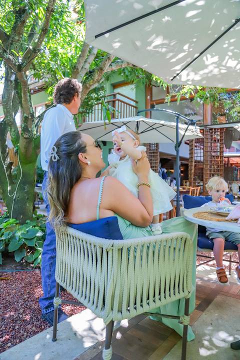 Família reunida na Pousada Refúgio da Vila celebrando o batismo de Catarina com simplicidade e aconchego.'