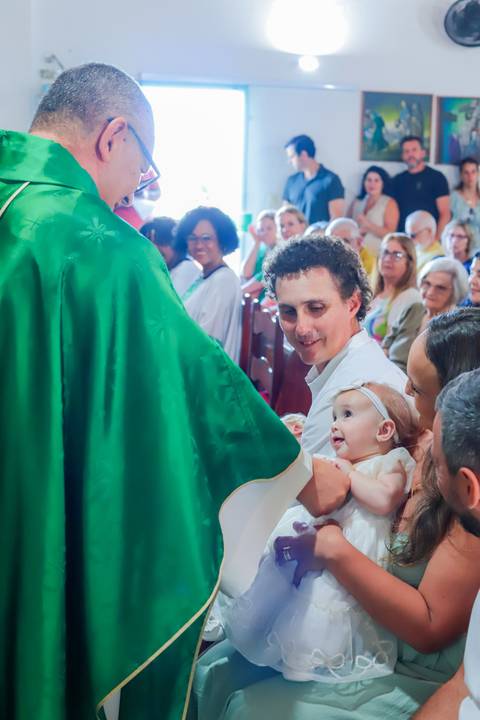 Ensaio de família em Praia do Forte com pais e filha durante o batismo — fotografia afetiva e natural realizada por Waldyr Lantyer.'