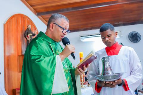 Pais emocionados segurando a bebê Catarina durante o batizado em Praia do Forte, com cenário encantador e luz suave da manhã.'