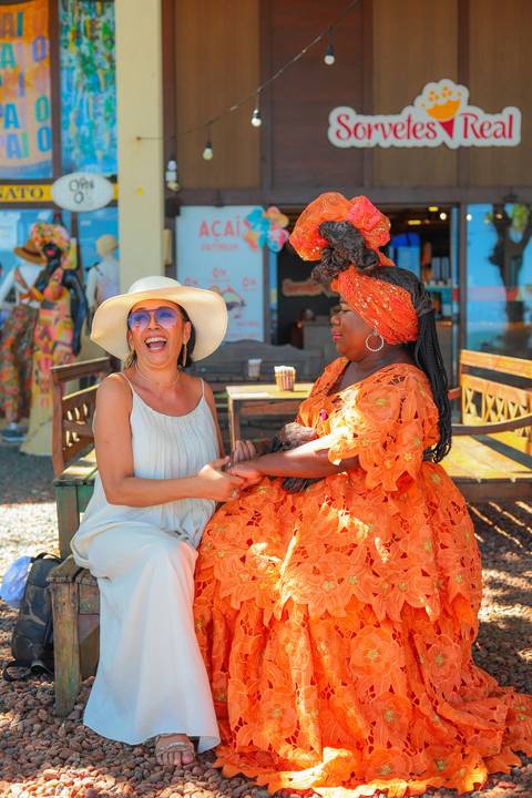 Turistas aproveitando a beleza dos coqueiros e da natureza exuberante de Praia do Forte. Fotógrafo especializado em ensaios na Bahia. O que fazer em Praia do Forte? Registrar memórias. Registro autêntico com a baiana sem freio em frente à igreja de São Fr'