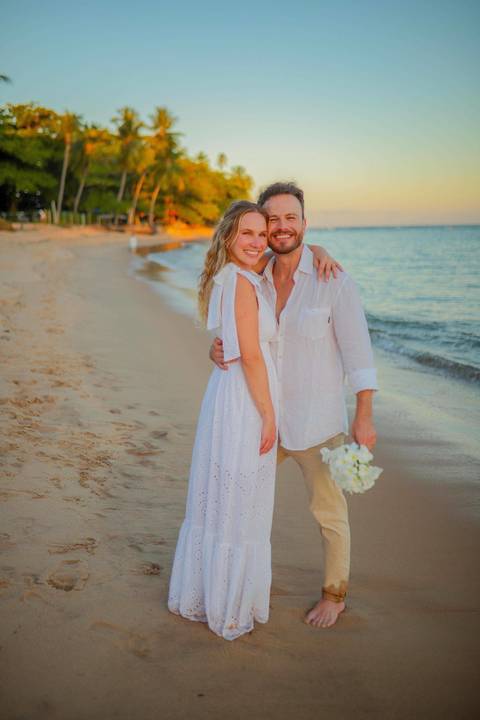 O que fazer em Praia do Forte Bahia, Fotógrafo em PRAIA DO FORTE BAHIA, WALDYR LANTYER.  Casal recém-casado celebrando elopement wedding na Praia do Forte com o céu colorido do crepúsculo ao fundo.'