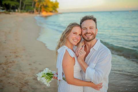 O que fazer em Praia do Forte Bahia, Fotógrafo em PRAIA DO FORTE BAHIA, WALDYR LANTYER.  Casal recém-casado celebrando elopement wedding na Praia do Forte com o céu colorido do crepúsculo ao fundo.'