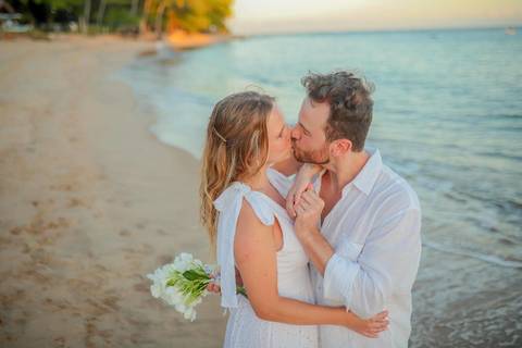 O que fazer em Praia do Forte Bahia, Fotógrafo em PRAIA DO FORTE BAHIA, WALDYR LANTYER.  Casal recém-casado celebrando elopement wedding na Praia do Forte com o céu colorido do crepúsculo ao fundo.'
