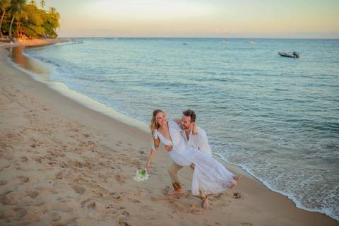 O que fazer em Praia do Forte Bahia, Fotógrafo em PRAIA DO FORTE BAHIA, WALDYR LANTYER.  Casal recém-casado celebrando elopement wedding na Praia do Forte com o céu colorido do crepúsculo ao fundo.'