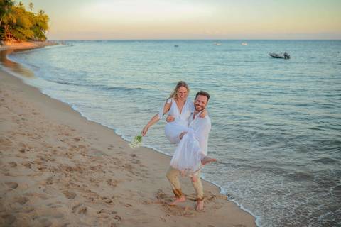 O que fazer em Praia do Forte Bahia, Fotógrafo em PRAIA DO FORTE BAHIA, WALDYR LANTYER.  Casal recém-casado celebrando elopement wedding na Praia do Forte com o céu colorido do crepúsculo ao fundo.'