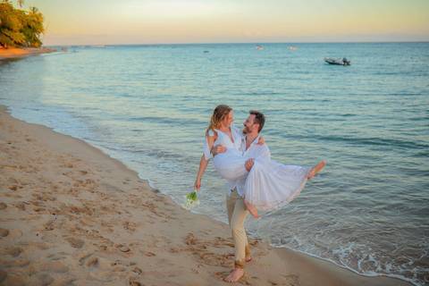 O que fazer em Praia do Forte Bahia, Fotógrafo em PRAIA DO FORTE BAHIA, WALDYR LANTYER.  Casal recém-casado celebrando elopement wedding na Praia do Forte com o céu colorido do crepúsculo ao fundo.'