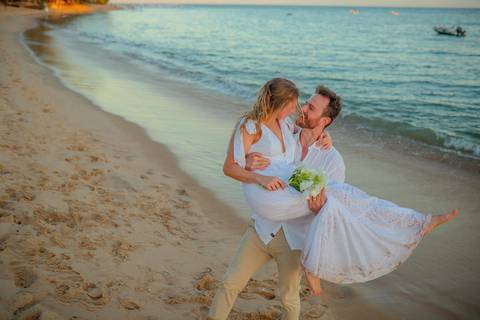 O que fazer em Praia do Forte Bahia, Fotógrafo em PRAIA DO FORTE BAHIA, WALDYR LANTYER.  Casal recém-casado celebrando elopement wedding na Praia do Forte com o céu colorido do crepúsculo ao fundo.'