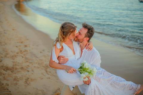 O que fazer em Praia do Forte Bahia, Fotógrafo em PRAIA DO FORTE BAHIA, WALDYR LANTYER.  Casal recém-casado celebrando elopement wedding na Praia do Forte com o céu colorido do crepúsculo ao fundo.'