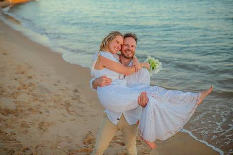 O que fazer em Praia do Forte Bahia, Fotógrafo em PRAIA DO FORTE BAHIA, WALDYR LANTYER.  Casal recém-casado celebrando elopement wedding na Praia do Forte com o céu colorido do crepúsculo ao fundo.'