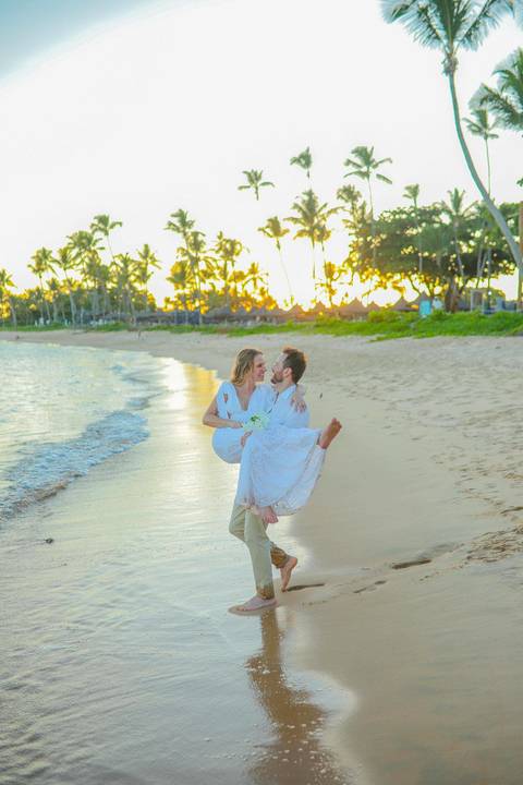 O que fazer em Praia do Forte Bahia, Fotógrafo em PRAIA DO FORTE BAHIA, WALDYR LANTYER.  Casal recém-casado celebrando elopement wedding na Praia do Forte com o céu colorido do crepúsculo ao fundo.'