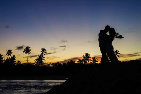 Silhuetas, mãos dadas e um céu em tons de laranja: assim registramos o pré-wedding de Bruna e Arley. Fotografia: Waldyr Lantyer. Foto de Praia do Forte.'