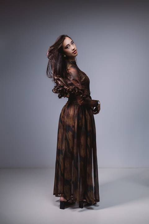 Layla com o segundo look do ensaio de 18 anos, em um retrato de corpo inteiro com fundo neutro e iluminação suave.'