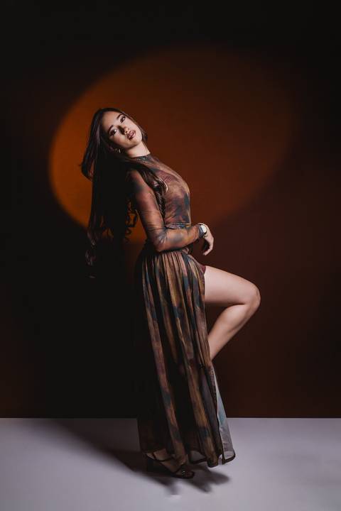Retrato de corpo inteiro de Layla com iluminação em tons quentes, criando uma atmosfera mais marcante para o ensaio de 18 anos.'