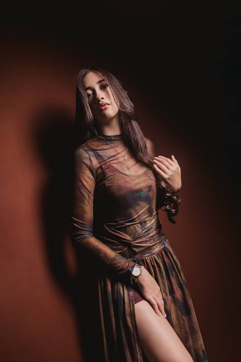 Layla posando diante de uma iluminação quente e marcante, encerrando a sequência de seu ensaio feminino de 18 anos em estúdio.'