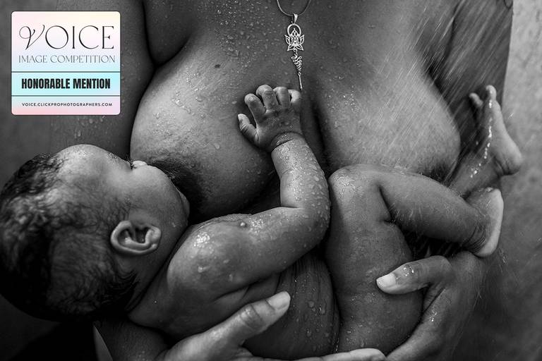 foto de Adriana Costa recebeu menção honrosa no conceituado concurso the Voice 2023 da Click Magazine e Click Pro na categoria Black & White de uma mãe amamentando seu bebê durante o banho de chuveiro