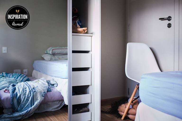 Foto de Adriana Costa de  dois irmãos brincando de esconder dentro do quarto foi premiada pela Inspiration Family Awards 