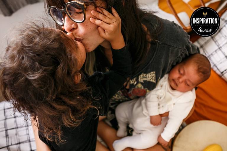 Adriana Costa foi premiada pela Inspiration Family Awards pela foto de uma filha beijando carinhosa sua mãe que está com um bebê de 2 meses no colo
