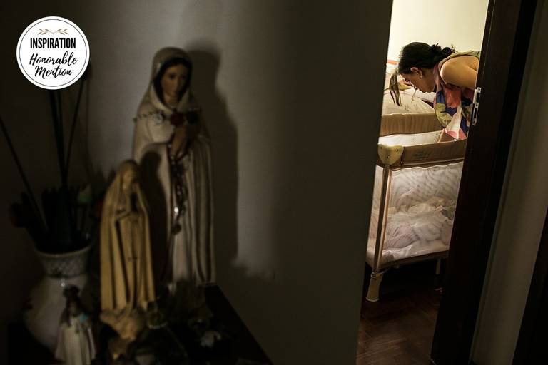 Adriana Costa foi premiada pela Inspiration Family Awards pela foto de uma mãe colocando sua bebê para dormir ao lado de imagens de santas enfatizando a fé religiosa e proteção