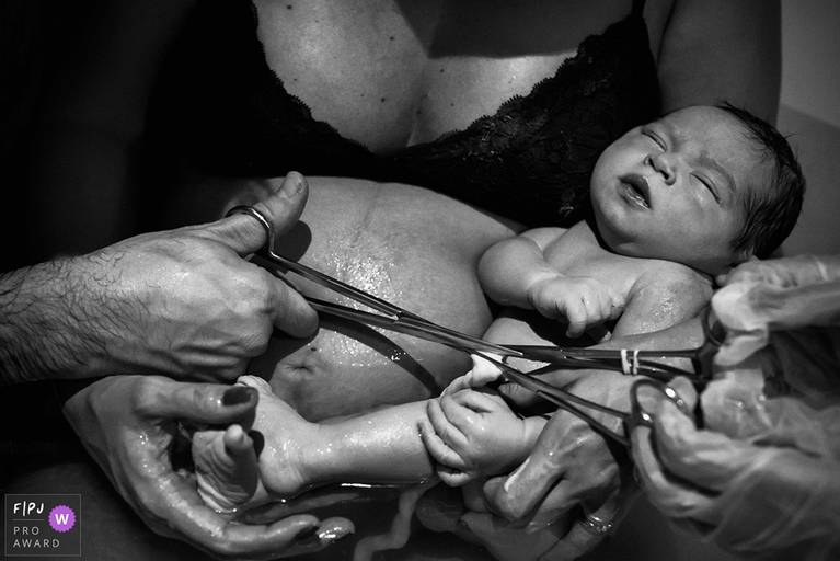 Foto de Adriana Costa do pai cortando o cordão umbilical do filho que acaba de nascer, premiada internacionalmente pela Associação FPJA (Family Photojournalist Association)